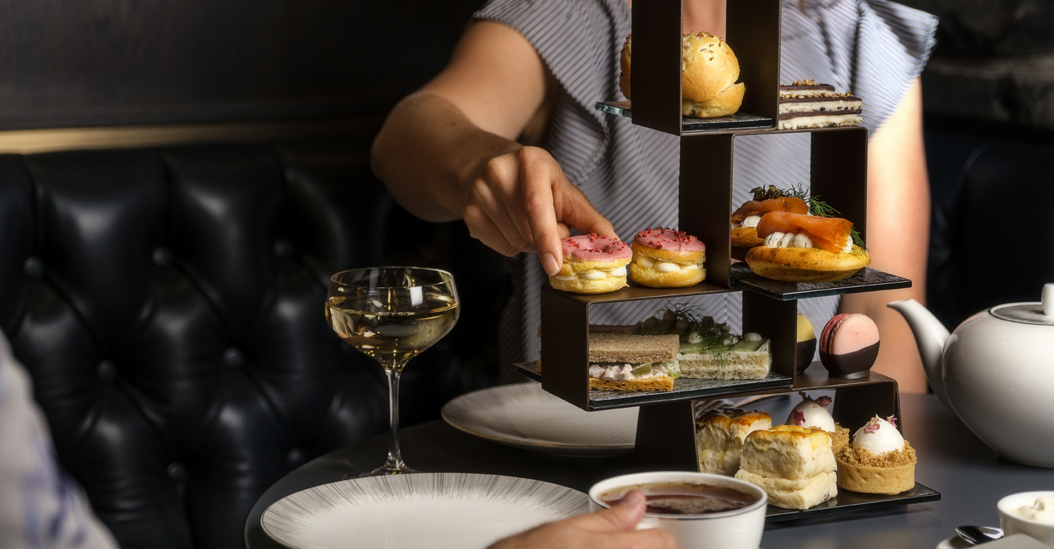 woman selecting a dessert during afternoon tea